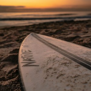 white surfboard on brown sand during sunset