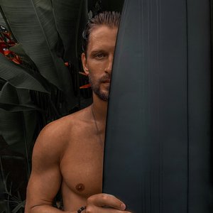 topless man holding black surfboard